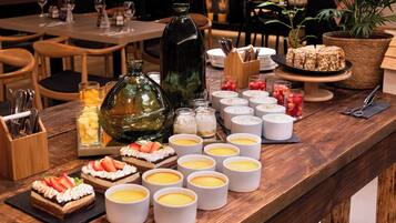 A buffet table with various desserts, including cakes and fruit tarts, and several white cups, likely containing beverages.