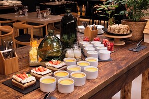 A buffet table with various desserts, including cakes and fruit tarts, and several white cups, likely containing beverages. - Mercure Concepcion (Concepción)