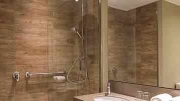 Un baño moderno con ducha de vidrio, tocador con lavabo y un espejo grande.