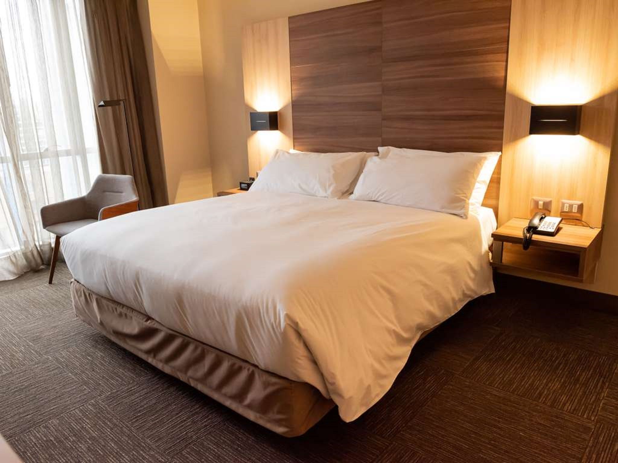 A large bed with two bedside tables, each with a phone and lamp.