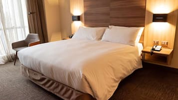 Uma cama grande com duas mesas de cabeceira, cada uma com telefone e luminária.