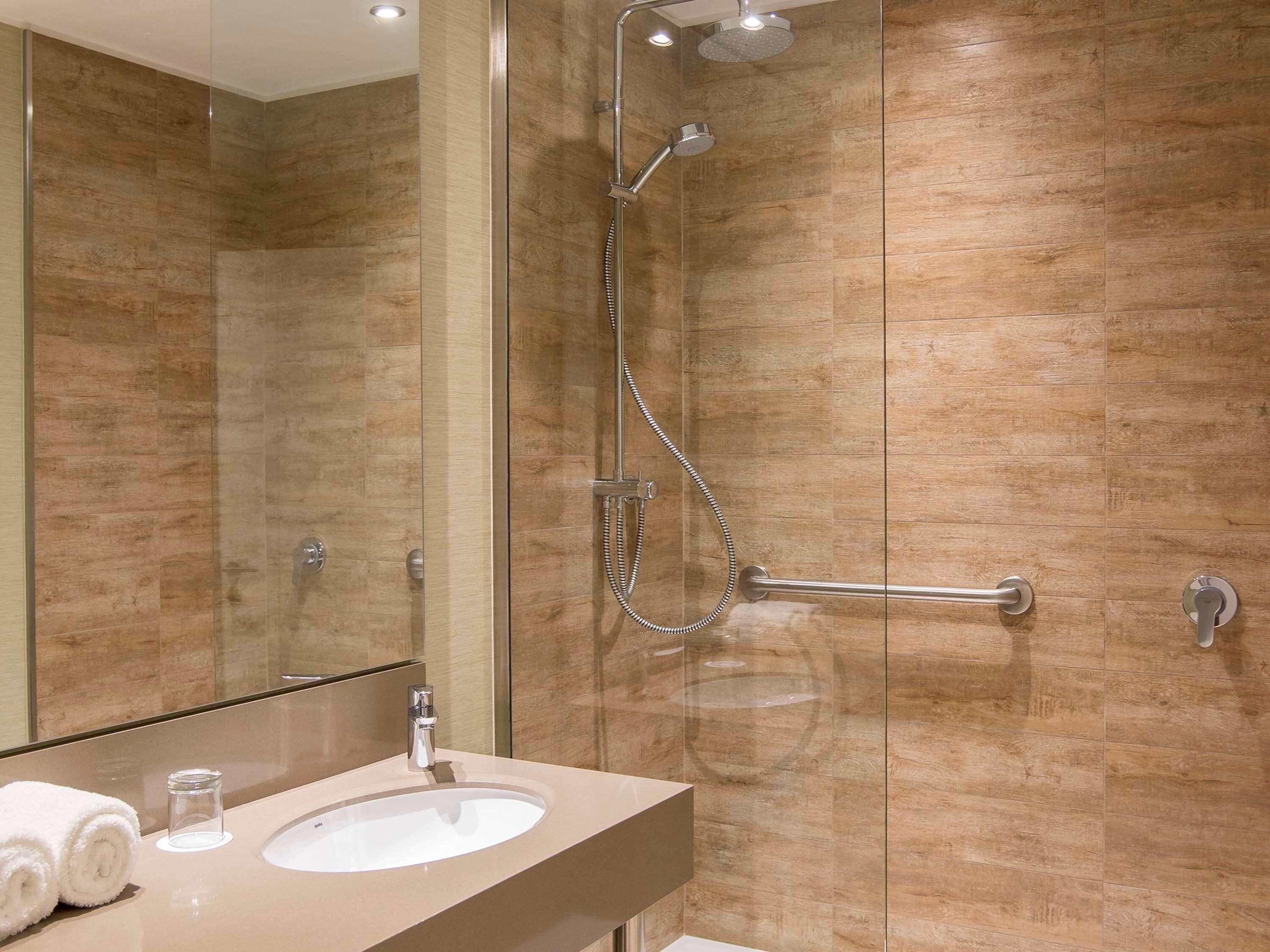 Un baño moderno con cabina de ducha de vidrio, tocador con lavamanos y espejo.