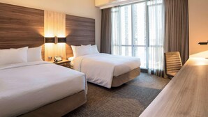 A hotel room with two beds, a desk, a chair, a lamp, and a window with curtains. - Mercure Concepcion (Concepción)