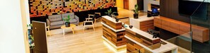 A modern interior with a reception desk, seating area, and a brick-patterned wall. - Mercure Concepcion (Concepción)