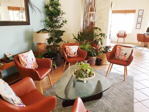 A modern lounge area with leather armchairs, a glass coffee table with a plant centerpiece, and various potted plants. - Quality Hotel Ballina (Ballina)