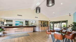A hotel lobby with a reception desk, seating area, and a view of the outdoors. - Quality Hotel Ballina (Ballina)