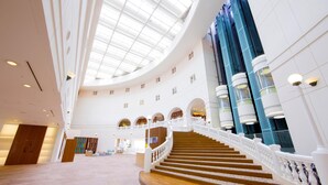A spacious atrium with a high ceiling, a central staircase, and multiple levels with arched doorways. - ANA Holiday Inn Resort Miyazaki (Miyazaki)