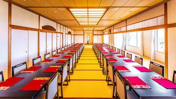 A conference room with long tables, chairs, and a yellow carpet.