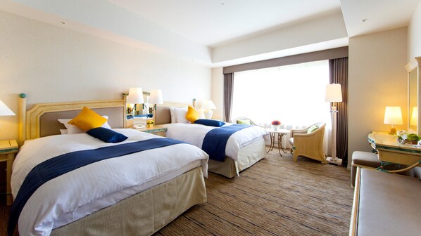 Habitación de hotel con dos camas, zona de estar y baño.