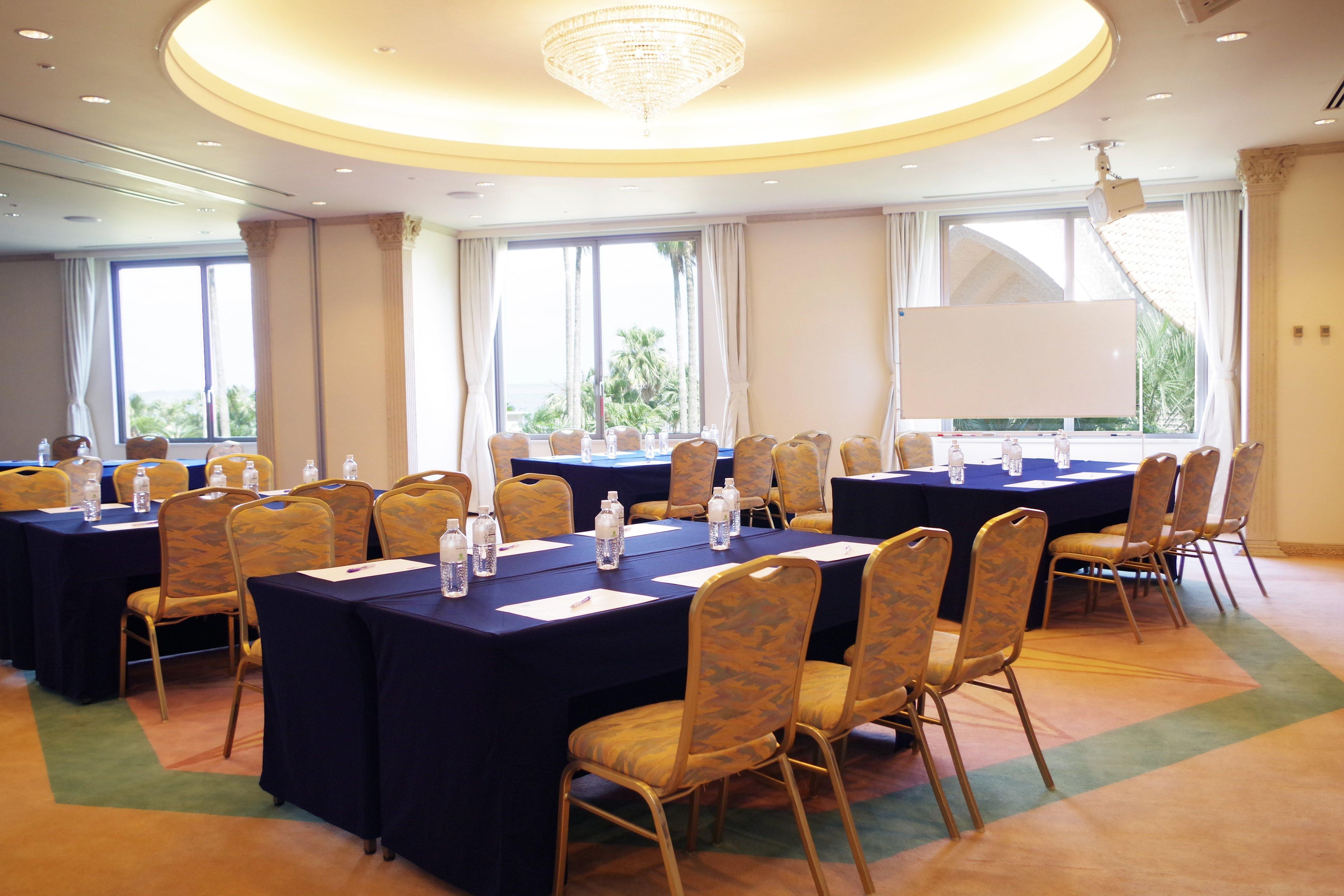 A conference room with multiple tables, chairs, and a large screen.