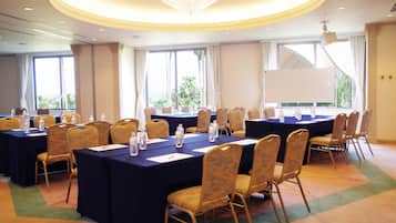 A conference room with multiple tables, chairs, and a large screen.