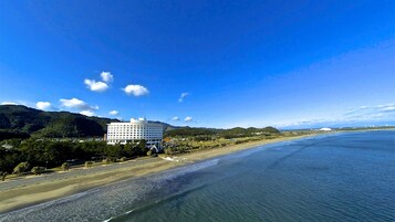 Un hotel frente al mar con vistas a la playa, un edificio grande y un cielo despejado.