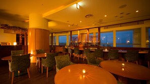 Un área de bar con varias opciones de asientos y vistas a la ciudad.