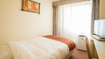 A hotel room with a bed, a television, and a window with curtains.