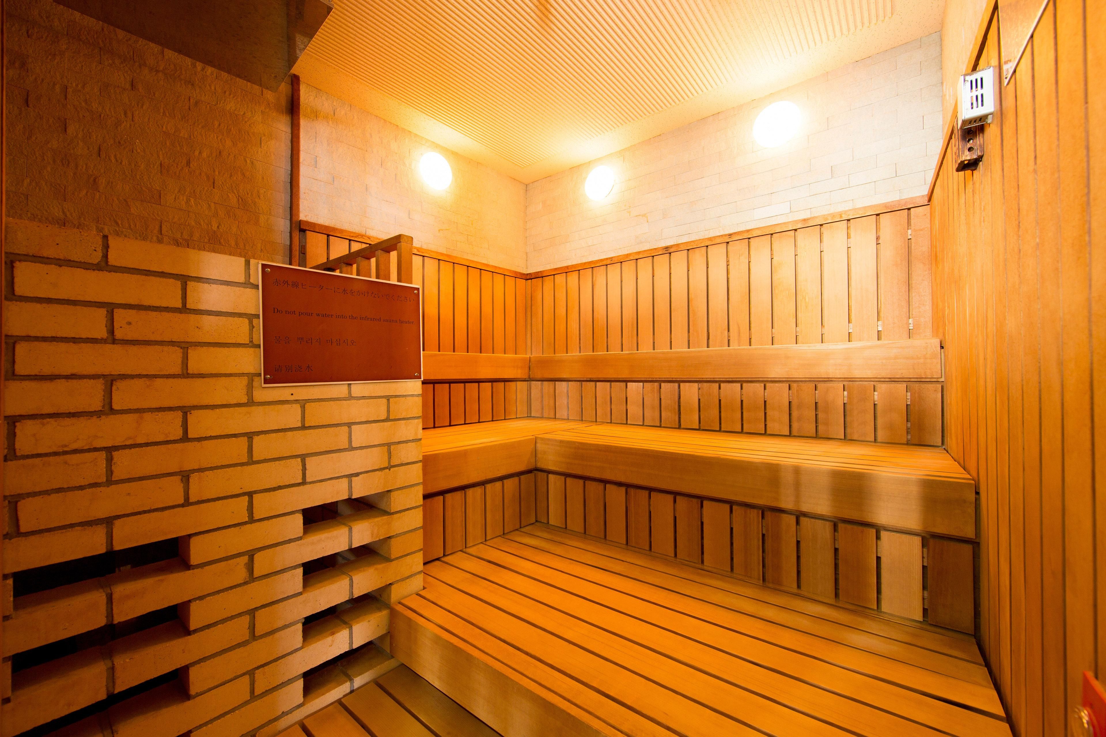 A sauna with wooden benches and a brick wall.