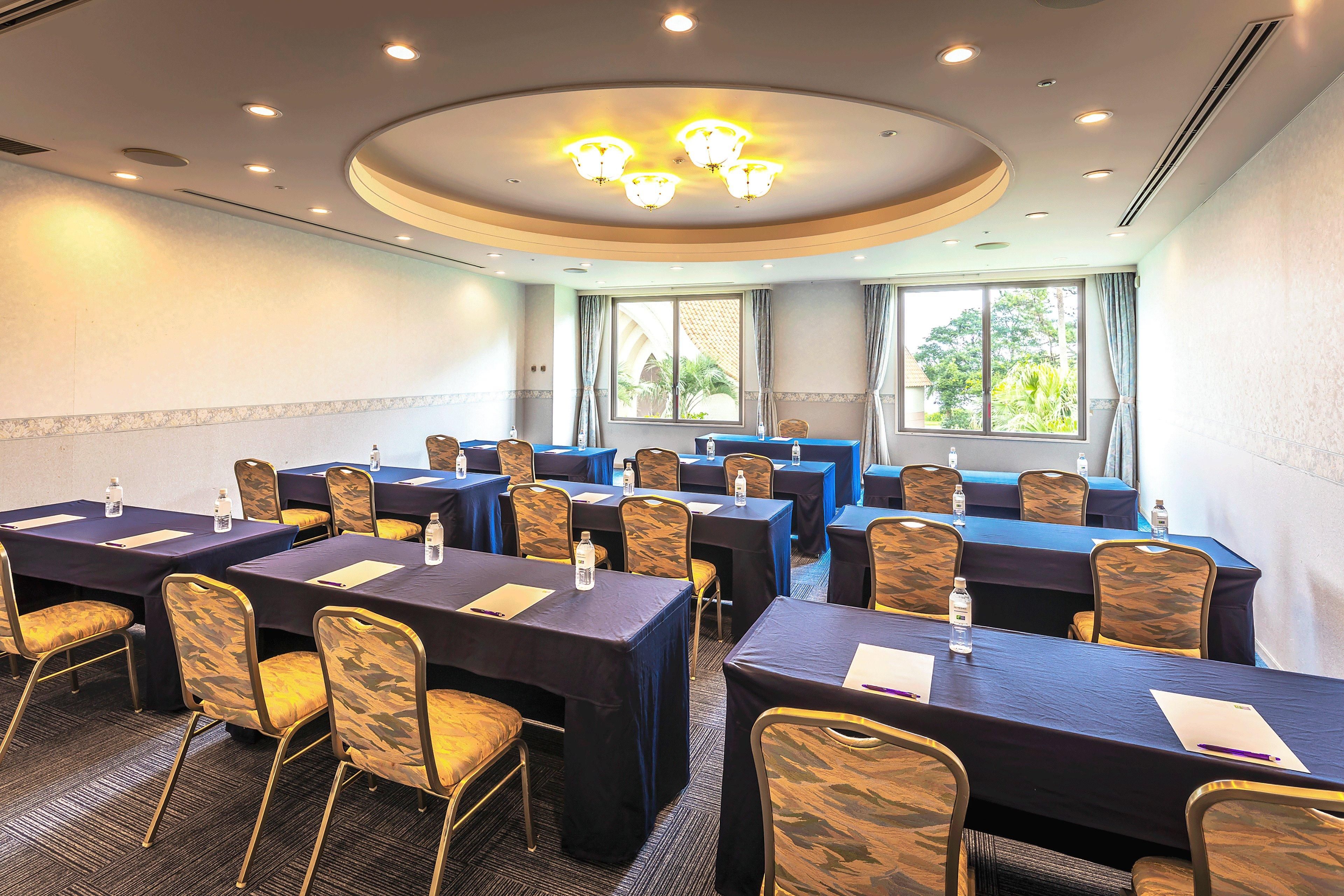 A conference room with tables, chairs, and a ceiling light fixture.
