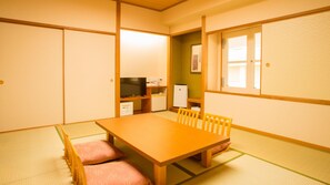 A traditional Japanese room with tatami flooring, a wooden table, and a television.