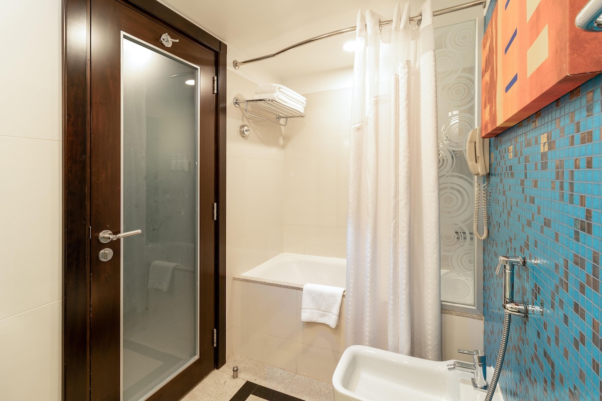 A bathroom with a glass door, a bathtub, a shower, and a sink.