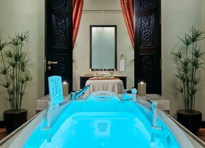 A spa area with a hot tub, a mirror, a sink, and two potted plants. - Holiday Inn Kuwait Al Thuraya City (Farwaniya)