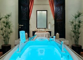 A spa area with a hot tub, a mirror, a sink, and two potted plants.