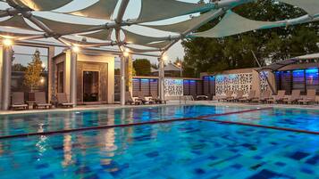 A swimming pool with lounge chairs and umbrellas, surrounded by a modern architectural design.