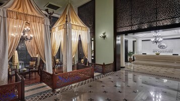 A luxurious lobby with ornate curtains, a reception desk, and a patterned floor.