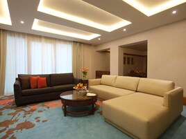 A modern living room with a dark patterned sofa, a beige sofa, and a coffee table with fruit and a vase.