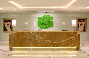 A reception desk with a marble top, a green logo, and framed portraits on either side.
