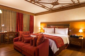 A hotel room with a large bed, a sofa, a desk with a lamp, and a nightstand with a lamp. - Holiday Inn Kuwait Al Thuraya City (Farwaniya)