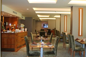 Un comedor de hotel con bar, varias mesas y sillas.