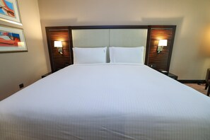 A hotel room with a large bed, two bedside lamps, and a headboard with a textured design. - Holiday Inn Kuwait Al Thuraya City (Farwaniya)