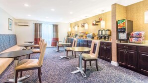 A hotel room with a seating area, a kitchenette, and a refrigerator stocked with beverages. - Dulles Suites (Sterling)