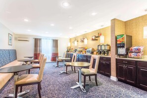 A hotel room with a seating area, a kitchenette, and a refrigerator stocked with beverages.