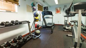 A gym with dumbbells, a treadmill, and weight plates. - Dulles Suites (Sterling)