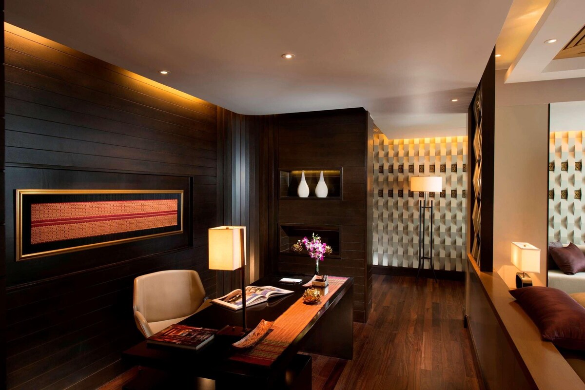 A modern hotel lobby with a reception desk, seating area, and decorative wall panels.