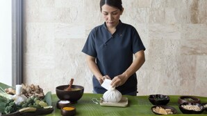 A person preparing food with various ingredients and utensils on a table. - Conrad Koh Samui Resid (Koh Samui)