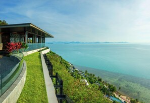 A modern building with a glass facade overlooking a coastal area. - Conrad Koh Samui Resid (Koh Samui)