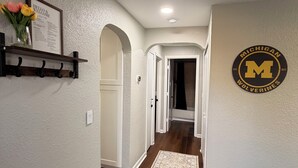 A hallway with a wooden floor, a rug, a welcome sign, and a Wolverines logo on the wall.