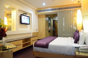 A hotel room with a bed, a TV, a desk, and a mirror.