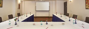 A conference room with a long table, chairs, a whiteboard, and floral centerpieces. - Airport Hotel Grand (New Delhi)