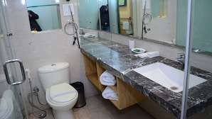 Un baño con inodoro, lavamanos, espejo y ducha.