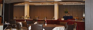 Un salón de conferencias con mesas redondas, sillas y un escenario con un atril.