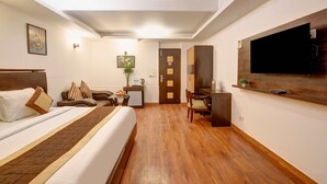 Una habitación de hotel con cama, escritorio, silla, televisión y puerta.
