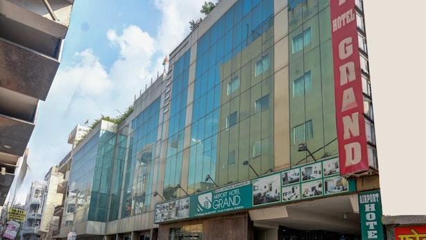 Un edificio de varios pisos con un cartel rojo llamativo para el Hotel Grand Airport.