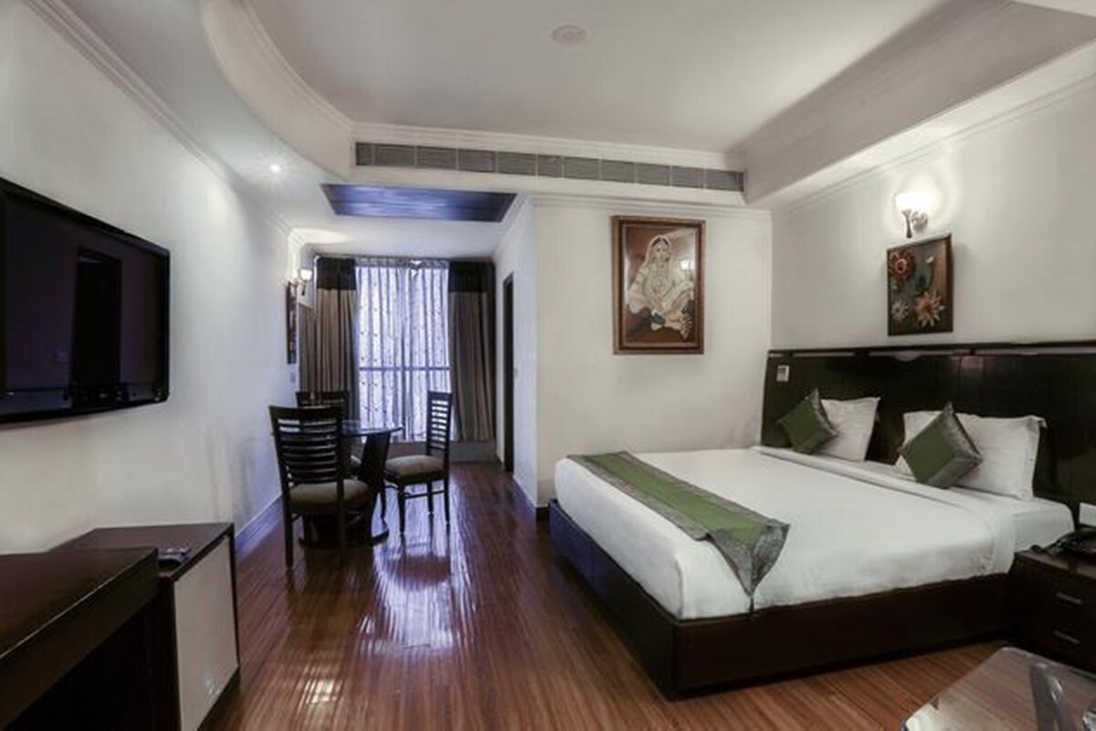 Una habitación de hotel con una cama grande, un escritorio y un televisor.