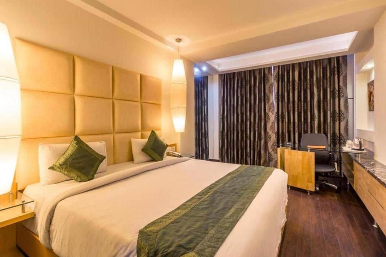 A hotel room with a large bed, a desk, and a chair.