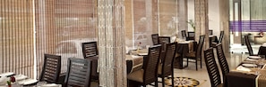 A restaurant with a modern design, featuring a mix of wooden and metal furniture, a patterned wall, and a clear view of the dining area.
