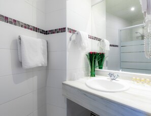 Une salle de bain moderne avec des carreaux blancs, un lavabo en marbre et une cabine de douche en verre.