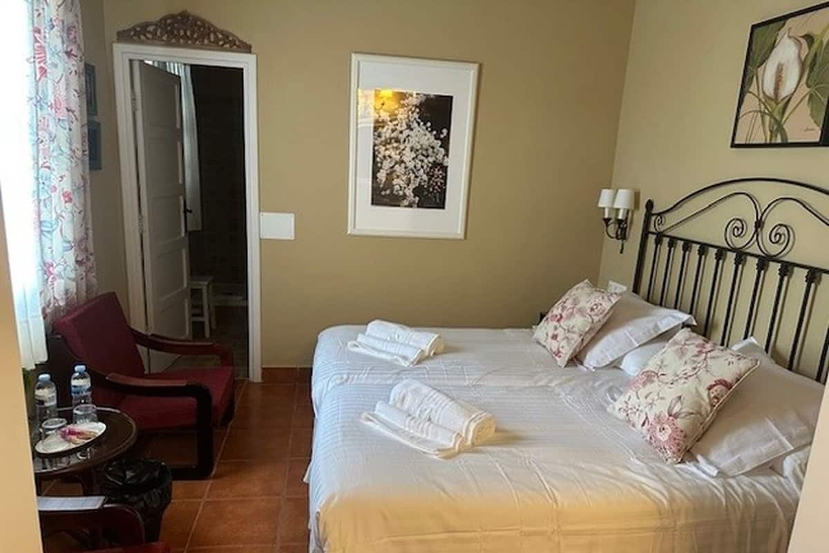 Habitación de hotel con cama, una silla, una mesa y botellas de agua.