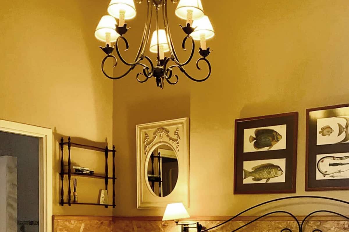 Una habitación de hotel con dos camas, un candelabro, un espejo y cuadros de peces en la pared.